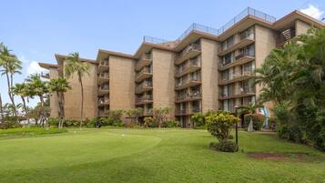A multi-story hotel with a brick facade, multiple balconies, and a well-maintained lawn.