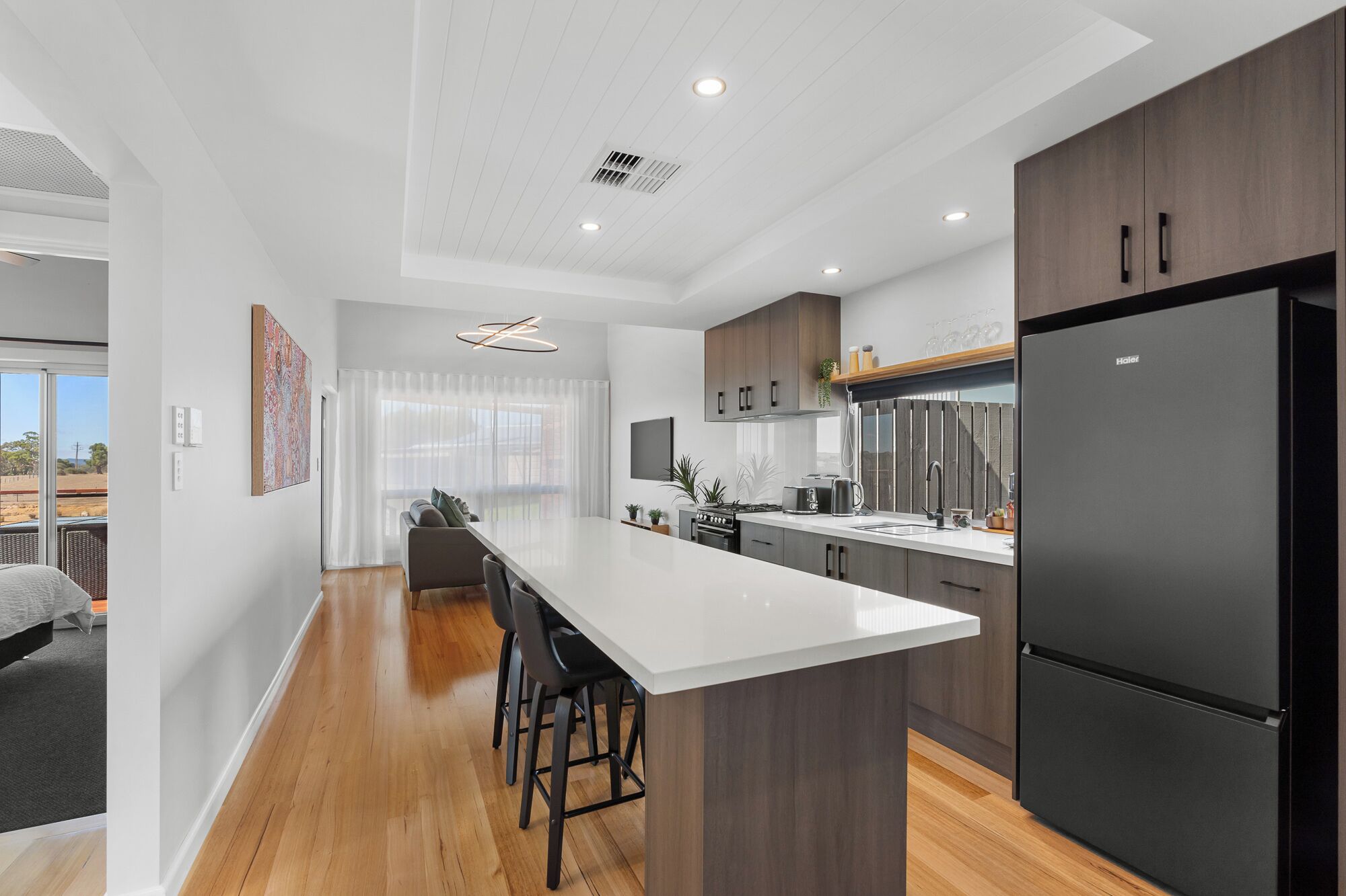 A modern kitchen with a central island, dark wood cabinets, and a black refrigerator.