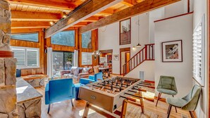 A spacious living area with a foosball table, blue sofas, and a stone accent wall.