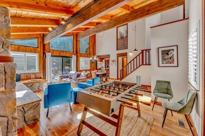 A spacious living area with a foosball table, blue sofas, and a stone accent wall.