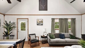 A spacious living area with a high ceiling, a dining table with chairs, a sofa with cushions, a side table with a lamp, and a large window with curtains. - Mountain retreat chalet w/ hot tub & deck (Rio)