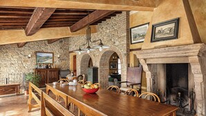 Un comedor rústico con una mesa y bancos de madera, paredes de piedra y una chimenea.