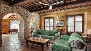 Un interior rústico con un arco de piedra, vigas de madera en el techo y un sofá tapizado en verde.