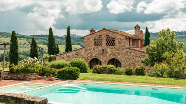 Un edificio de piedra con una piscina delantera.