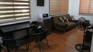 A living room with a desk, two chairs, a sofa, and a standing fan. - Casa Rafael Coron (Coron)