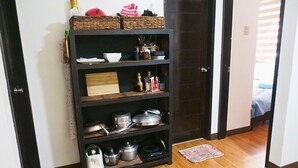 A kitchen with a dark wooden shelf unit holding various kitchen items and cookware. - Casa Rafael Coron (Coron)