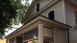 Une maison à deux étages avec une grande baie vitrée au rez-de-chaussée, un porche couvert et un panneau indiquant qu’il s’agit d’une propriété privée.
