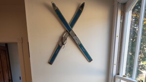 Un escalier avec une rampe en bois, un porte-skis fixé au mur et une fenêtre donnant sur l’extérieur.