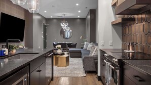 A modern kitchen with a central island, a dining area with a round table, and a living space with a sofa. - French’s Loft | Luxe Stay Near Broadway (Nashville)