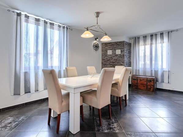 A dining area with a white table and chairs, a stone accent wall, and a vintage trunk.