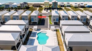 Un complexe hôtelier comprenant des bâtiments à plusieurs étages, une piscine centrale et offrant une vue sur la plage.