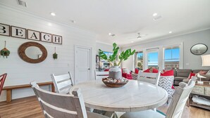 Un coin repas avec une table ronde, des chaises blanches et un récipient contenant des objets décoratifs.