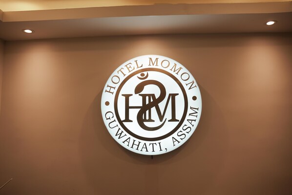 A circular logo with the text "HOTEL MOMON GUWAHATI, ASSAM" and a stylized 'H&M' emblem. - Hotel Momon (Guwahati)