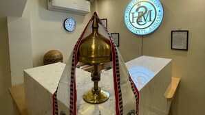 Uma área de recepção com balcão de mármore, luminária de latão e ventoinha no teto.