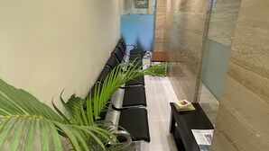 Uma área de recepção com um longo banco, balcão de atendimento e plantas em vasos.