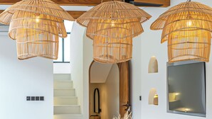 Ein modernes Wohnzimmer mit einem Holzesstisch, einem weißen Sofa und drei Weidenpendelleuchten.