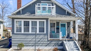 A two-story house with a blue door, a balcony, and a small front porch. - Beach Bungalow, walk to beach, private backyard (West Haven)