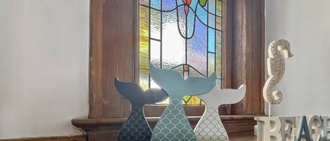 Un letrero de madera con el texto "SALTY KISSES, STARFISH WISHES" frente a una ventana con un diseño de vitral.