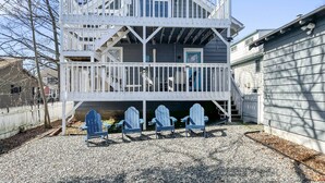 A two-story house with a balcony and three Adirondack chairs in front. - Beach Bungalow, walk to beach, private backyard (West Haven)