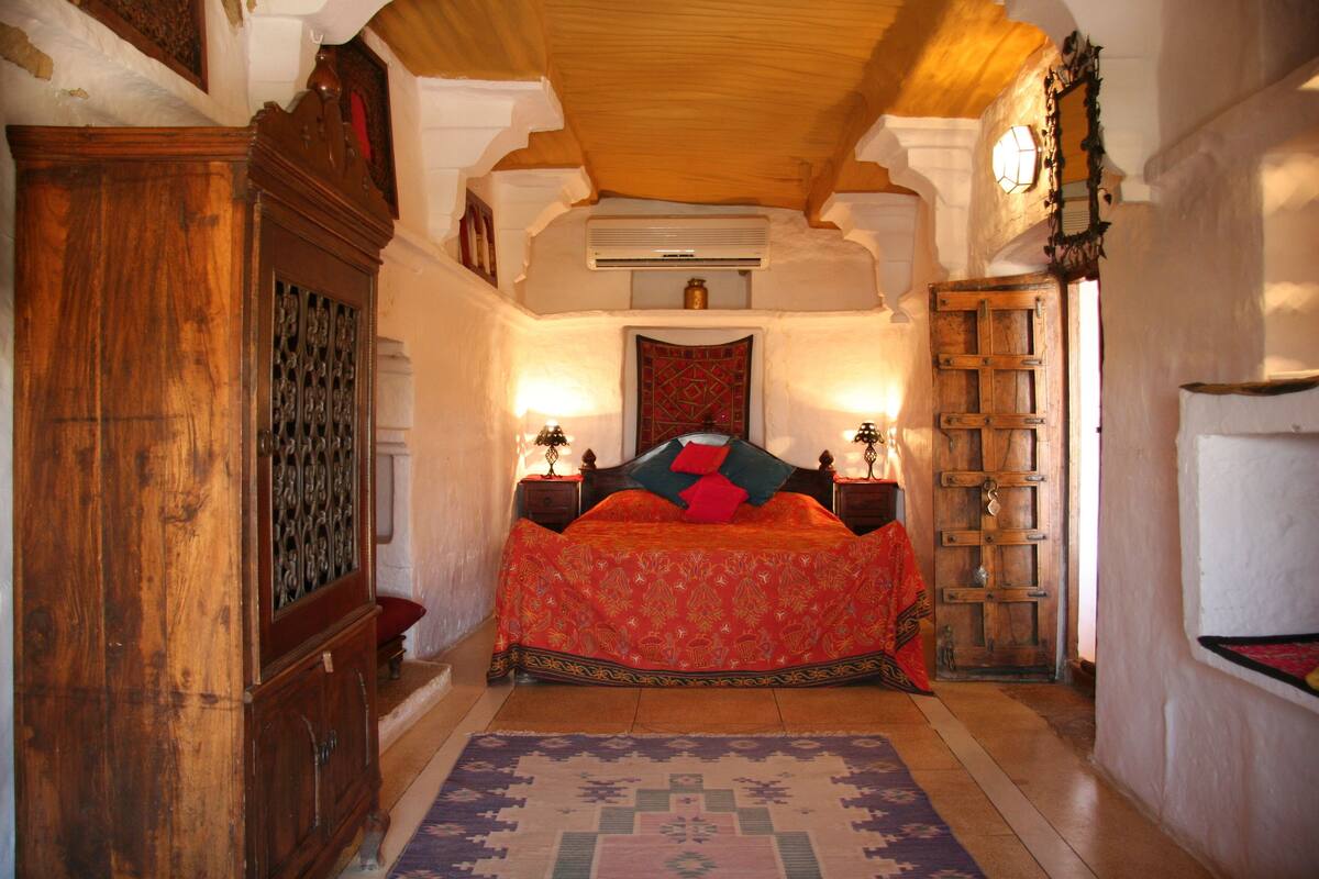 Une chambre de style traditionnel, avec un lit en bois, un tapis à motifs et une armoire en bois.
