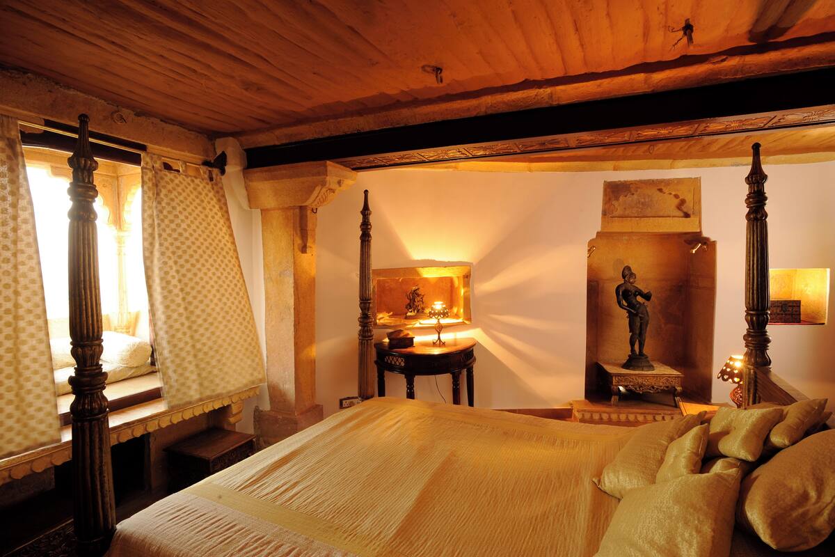 Une chambre à coucher avec un lit à baldaquin, une table de chevet, une lampe et une statue accrochée au mur.