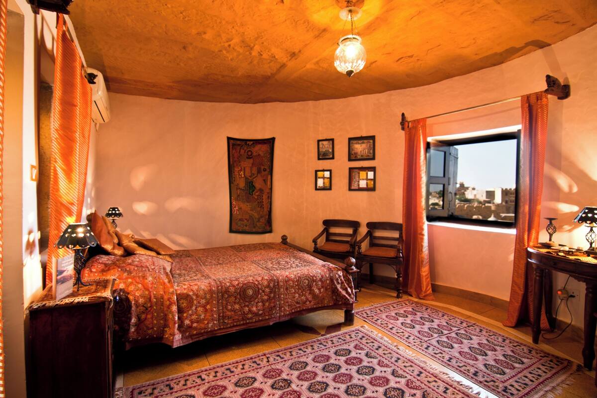 Une chambre à coucher avec un lit, deux chaises, une fenêtre et une lampe.