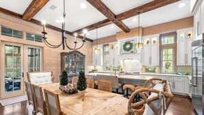 A spacious kitchen with wooden beams, a large island, and white cabinetry. - WaterColor Retreat with Beach Club Access, Golf Cart, and Private Pool for the Ultimate Escape! (Seagrove Beach)