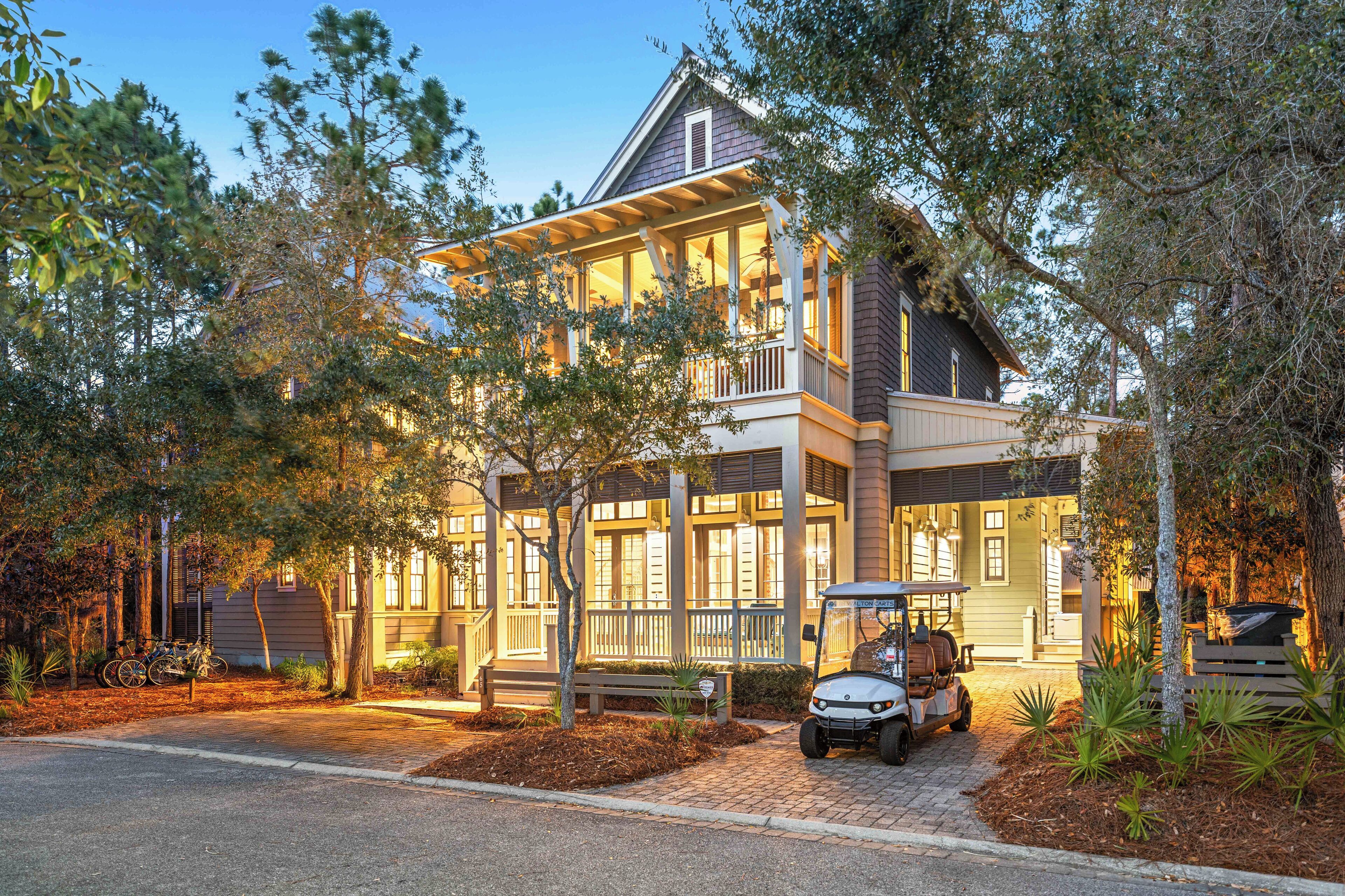 A two-story house with a porch, a covered patio, and a golf cart parked in front.