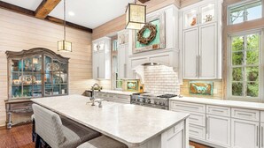 A spacious kitchen with white cabinetry, a large island, and a rustic wooden ceiling. - WaterColor Retreat with Beach Club Access, Golf Cart, and Private Pool for the Ultimate Escape! (Seagrove Beach)