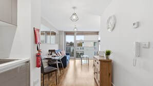 A modern kitchen with a dining area, wooden cabinets, a fire extinguisher, and a clock on the wall. - Properties Unique | Cherry (Newcastle Upon Tyne)