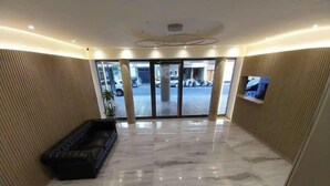 Un hall d’entrée spacieux, doté d’un sol en marbre, d’un canapé et d’un écran de télévision.