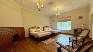 Une chambre avec deux lits, une cheminée en briques, un plancher en bois et une fenêtre donnant sur un beau paysage.