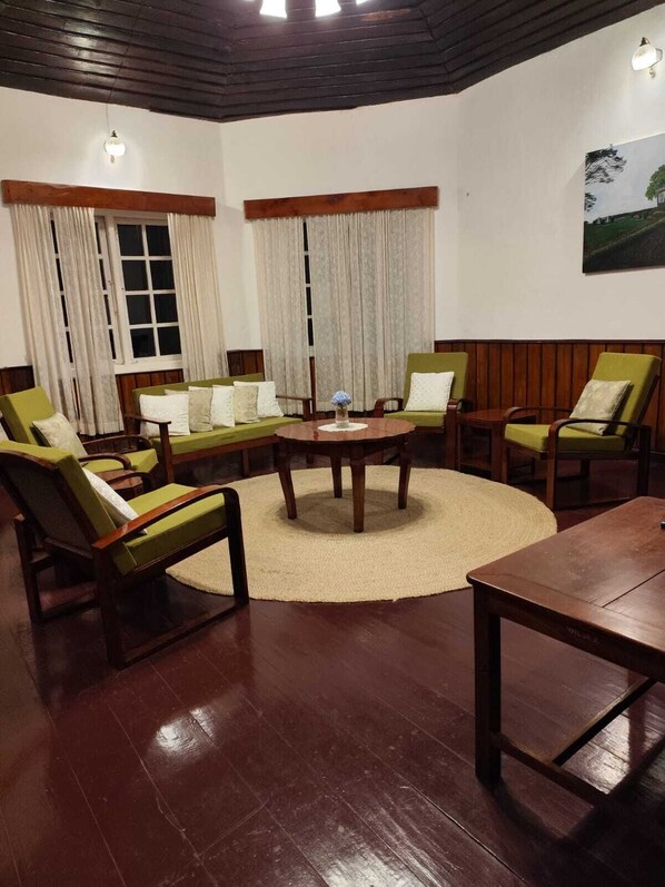 Una sala de estar acogedora con una mesa de centro de madera rodeada por sillones verdes y un sofá.