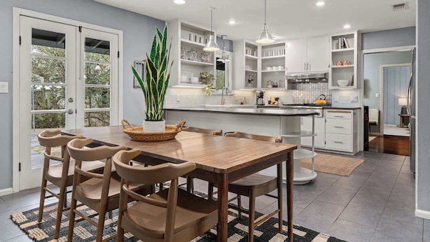 A modern kitchen with a central island, white cabinetry, and pendant lighting.