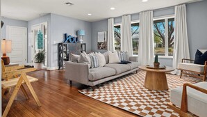 A modern living room with a grey sofa, wooden coffee table, and a checkered rug.