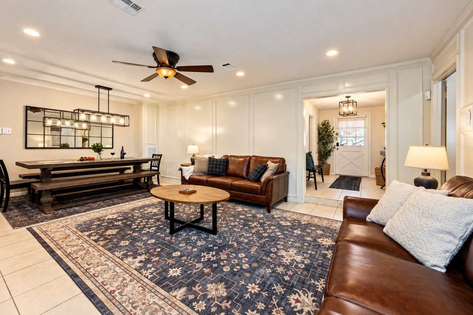 Un salon spacieux avec un canapé en cuir marron, une table basse ronde et un coin repas comprenant une banquette et une table.