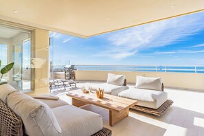Un balcon avec vue sur la mer, aménagé avec un canapé, une table et un barbecue.