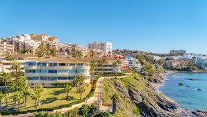 A coastal hotel with multiple floors, balconies, and a view of the beach.