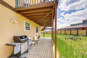 En overdækket terrasse med grill, stole og et bord.