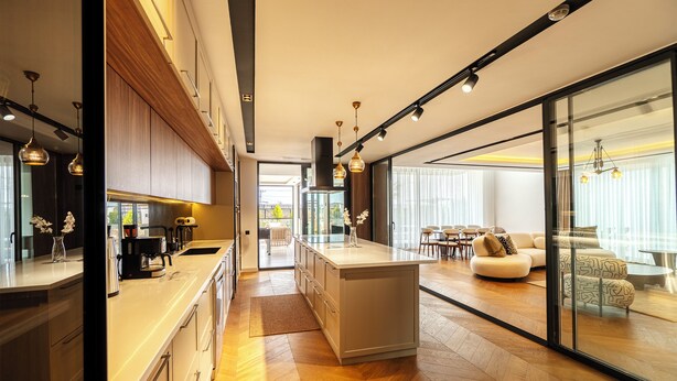 Une cuisine moderne dotée d’un îlot central, de meubles en bois et de luminaires suspendus.