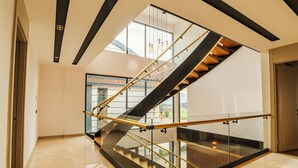 Un intérieur moderne avec un escalier à parois de verre, des planchers polis et un design minimaliste.