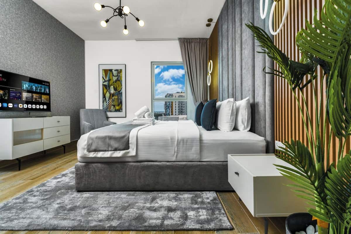 A modern bedroom with a bed, bedside table, and a TV on a stand.