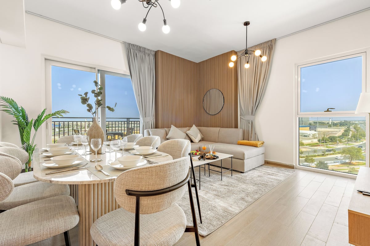 A modern living room with a dining area, large windows, and a view of the city.