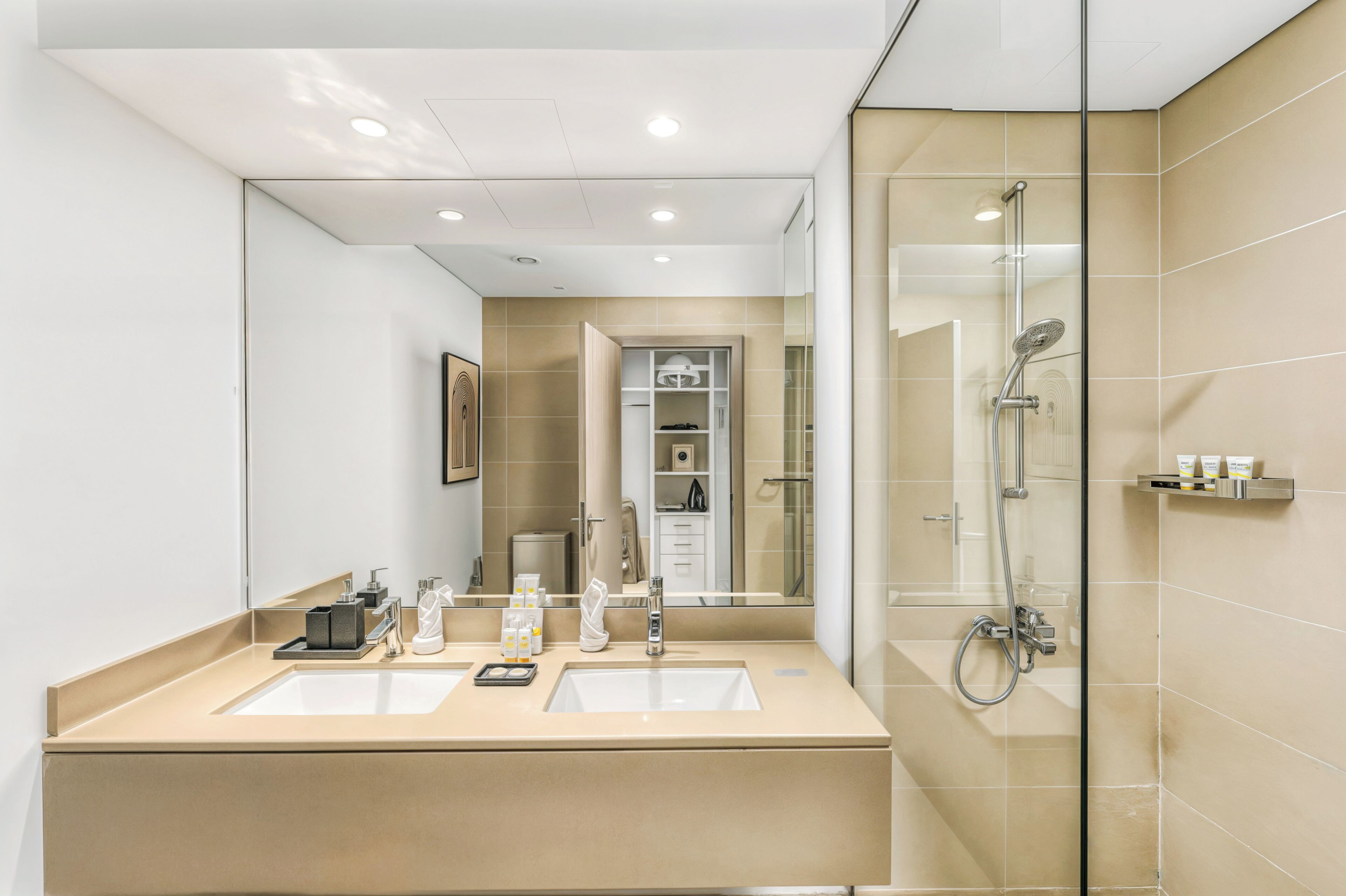 Een moderne badkamer met twee wastafels, een douchecabine van glas en een spiegel die de ruimte weerspiegelt.