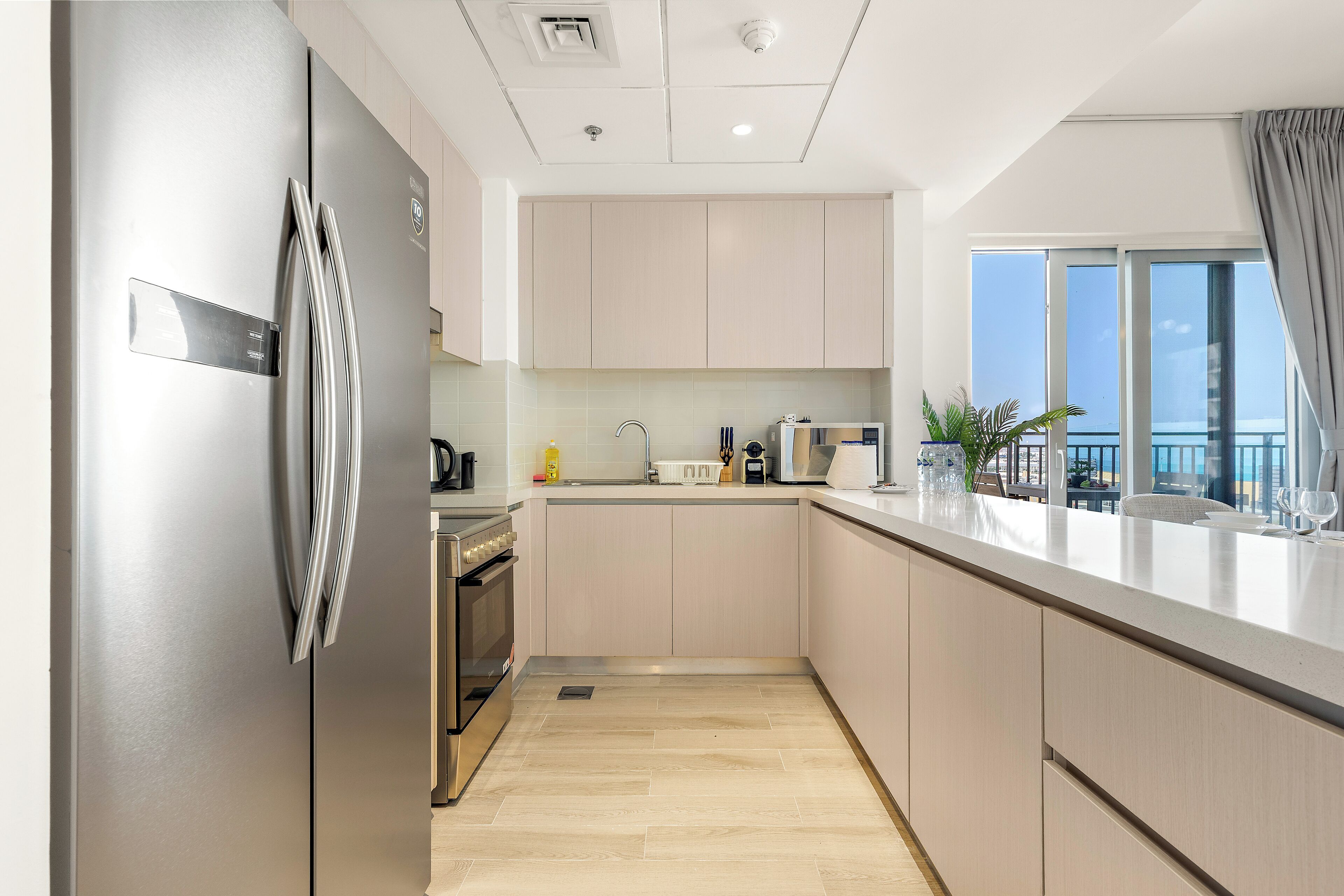 A modern kitchen with a stainless steel refrigerator, a built-in oven, and a sink.