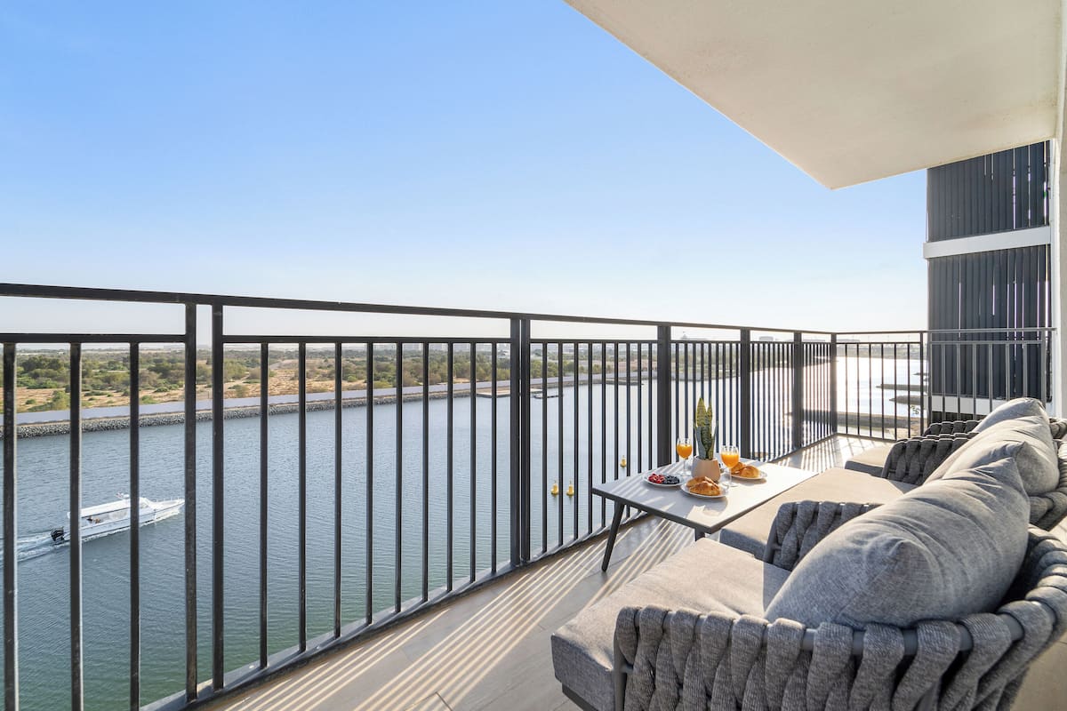 A balcony with a view of a river, a table with breakfast items, and a sofa.
