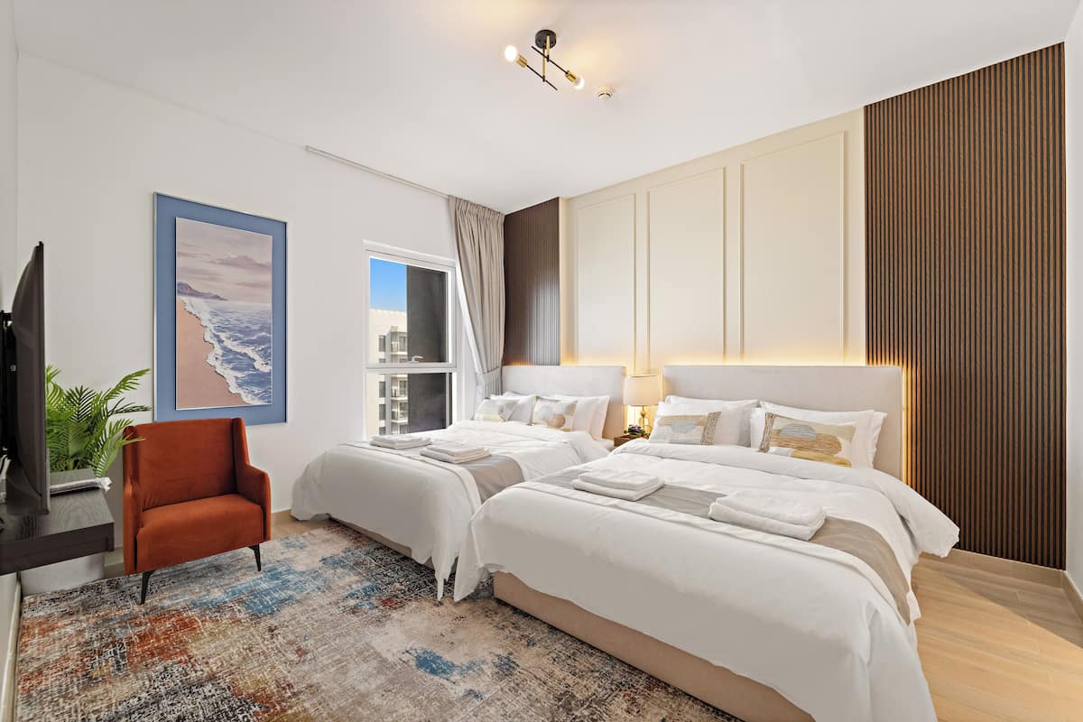 A modern hotel room with two beds, a large window, a plant, and a view of the city.