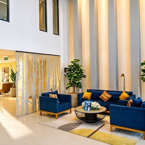 Un vestíbulo moderno con un sofá azul, una mesa de centro redonda y una planta decorativa.