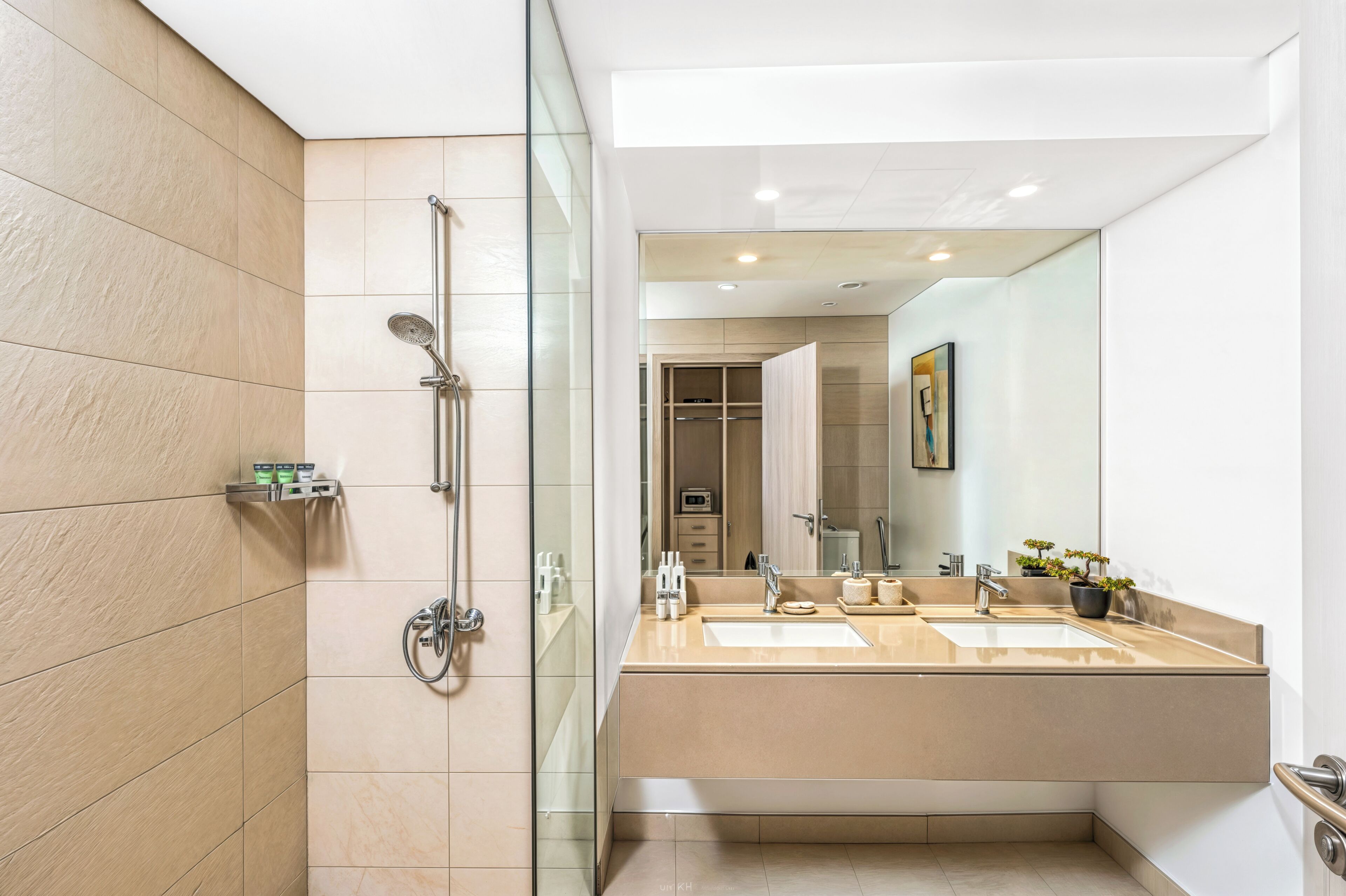 Une salle de bain moderne avec une douche à parois de verre, un meuble-lavabo à deux vasques et un grand miroir.