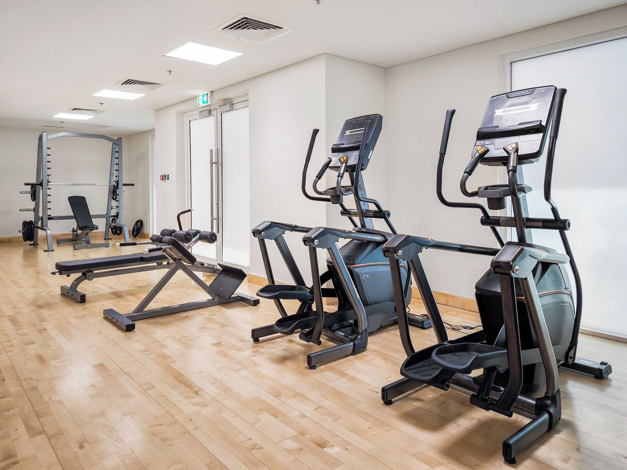 Ein Fitnessstudio mit Laufbändern, Kraftgeräten und einer Bank.